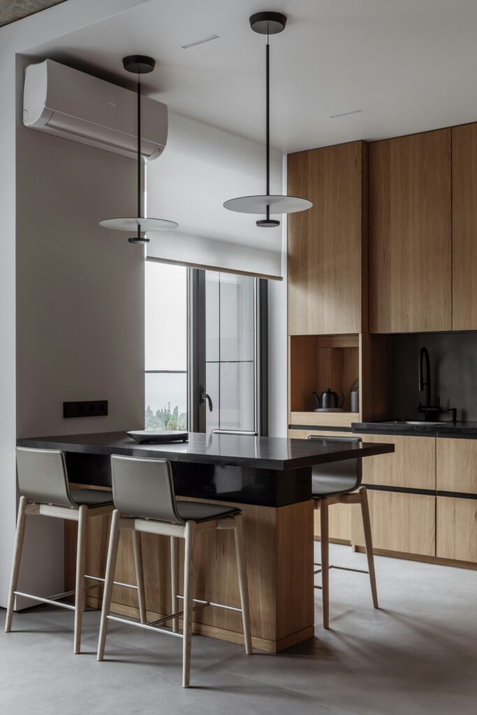Koyu tezgahlı, ahşap dolaplı ve uzun pencereli modern mutfak